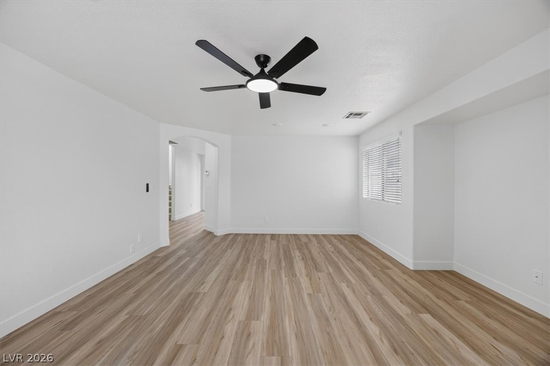 552 Albacate Street Henderson, NV 89015 - Photo 8 of 40 A spacious room with warm wood-look flooring and a modern ceiling fan, ready for personal touches.