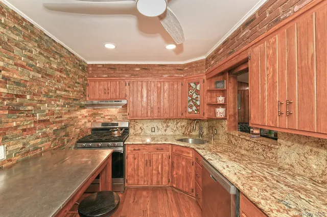 a kitchen with stainless steel appliances granite countertop a sink a stove and refrigerator