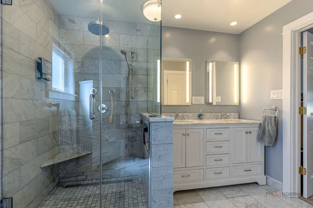 a bathroom with a double vanity sink a toilet a mirror and shower