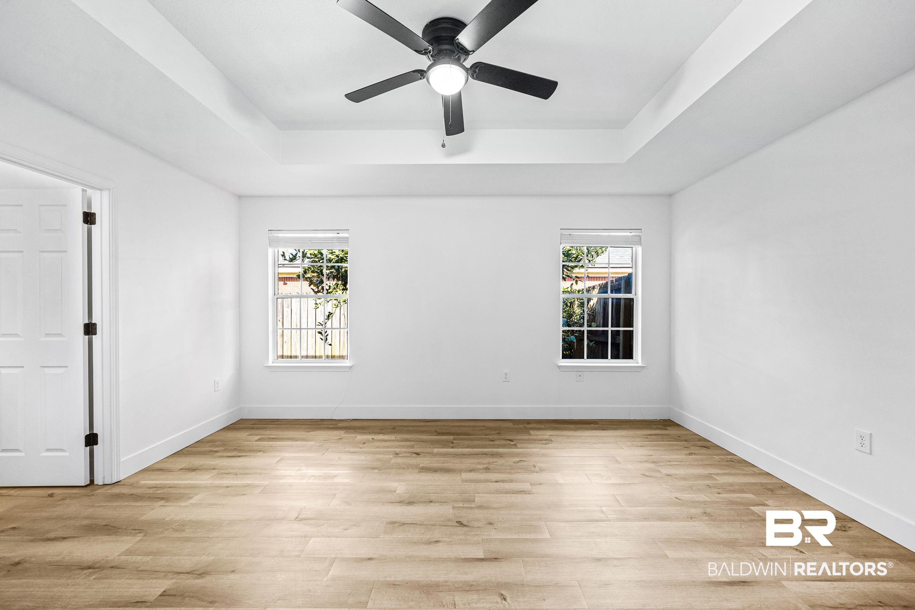 9243 Brookshire Loop Daphne, AL 36526 - Photo 9 of 26 Unfurnished room featuring a raised ceiling, ceiling fan, and light wood-type flooring