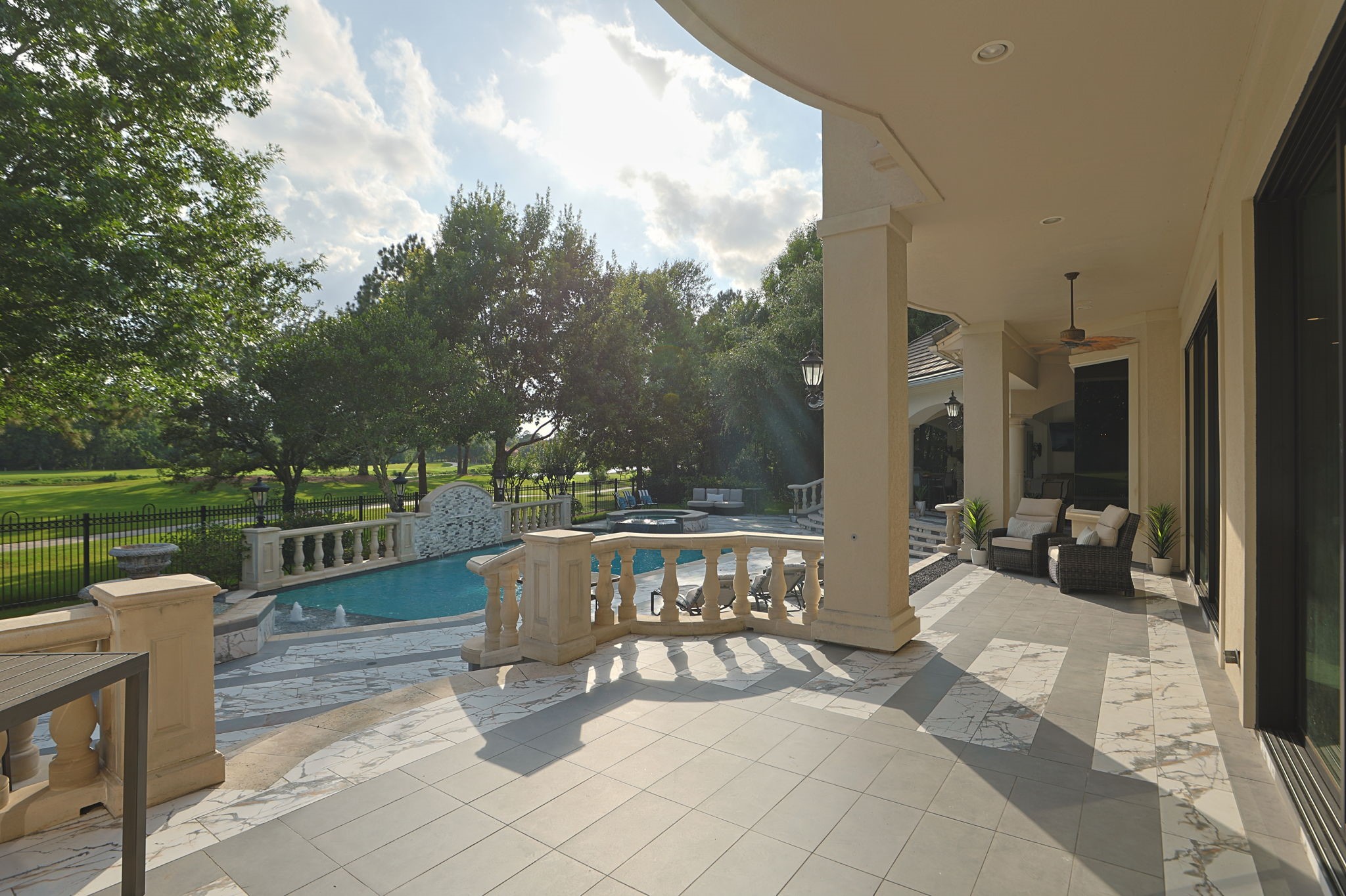 39 Maymont Way Spring, TX 77382 - Photo 36 of 50 This photo showcases a luxurious outdoor patio featuring elegant tiled flooring, a cozy seating area, and a view of a beautifully landscaped backyard with a pool. The area is surrounded by lush greenery, offering a serene and private setting.