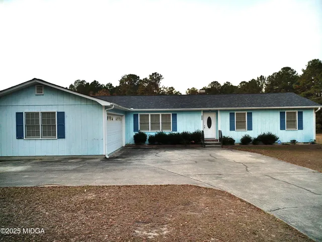 a front view of house with yard and trees in the background