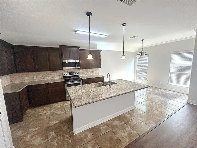 a kitchen with stainless steel appliances granite countertop a sink a stove and a refrigerator