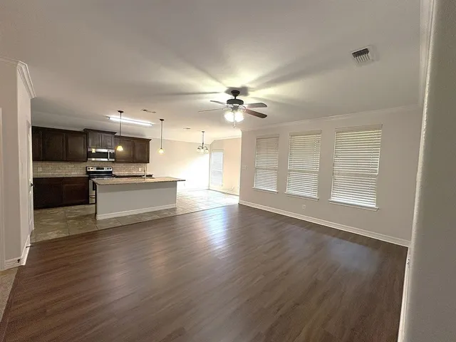 a view of an empty room with a kitchen and a window
