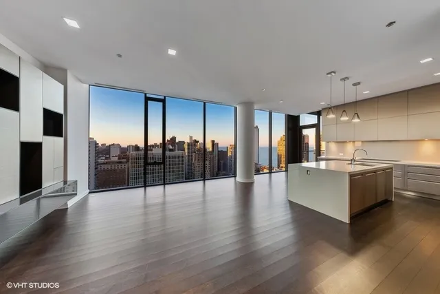 a view of an empty room with kitchen view and a flat screen tv