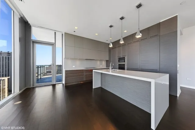 a view of a kitchen with kitchen island a sink wooden floor and stainless steel appliances