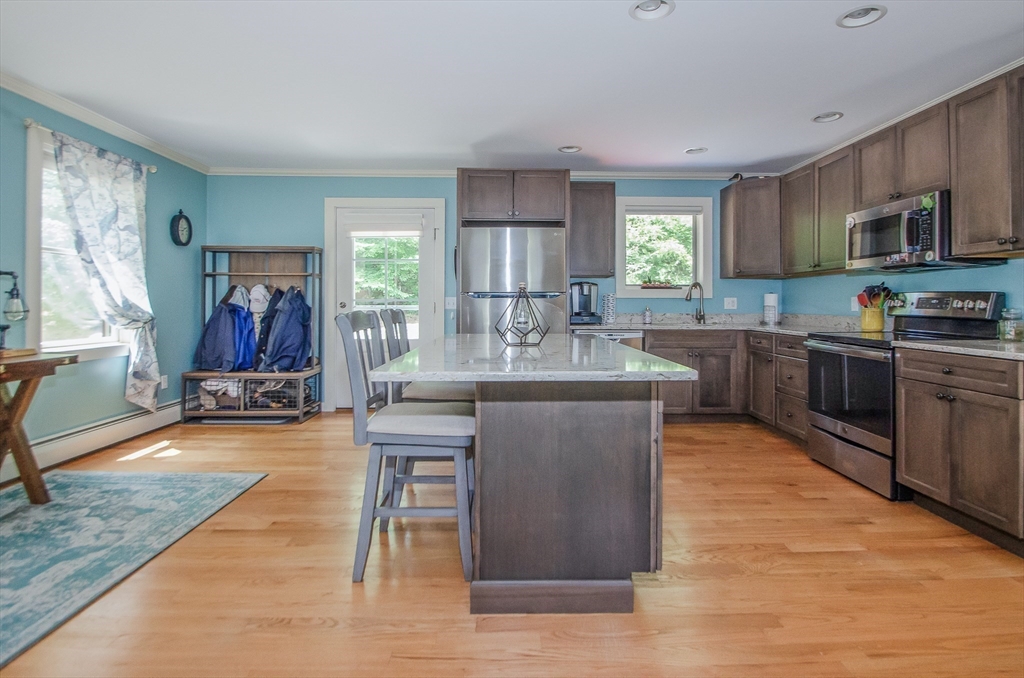 1-3 Doctor Hickey Lane Rochester, MA 02770 - Photo 26 of 38 a kitchen with stainless steel appliances granite countertop a stove top oven a sink dishwasher a dining table and chairs with wooden floor