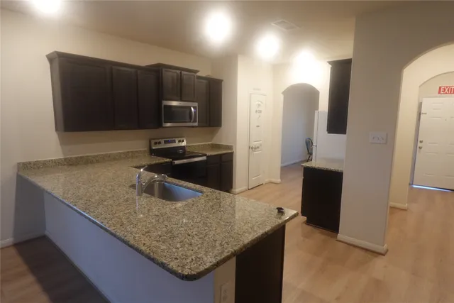 a kitchen with stainless steel appliances granite countertop a sink a microwave a refrigerator and a stove