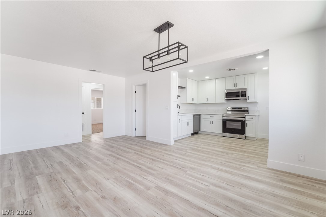 39 Lowery Street Henderson, NV 89015 - Photo 7 of 40 A seamless flow connects the living area to a modern kitchen, featuring sleek appliances and luminous recessed lighting.