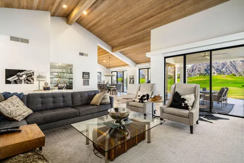 a view of a dining room with furniture one side kitchen view and wooden floor