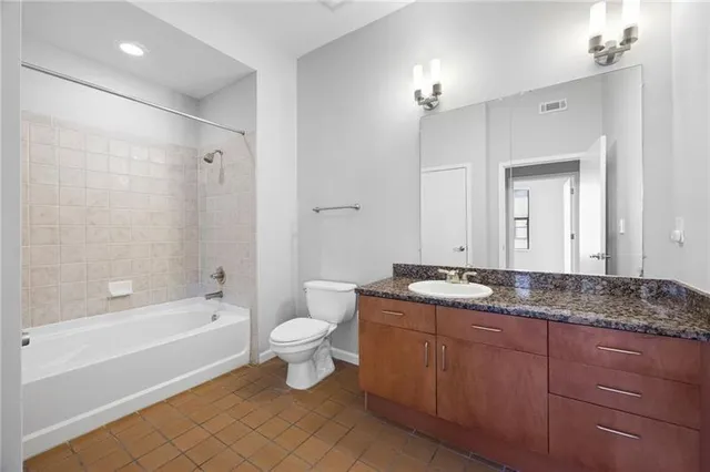 a bathroom with a granite countertop sink toilet mirror and bathtub