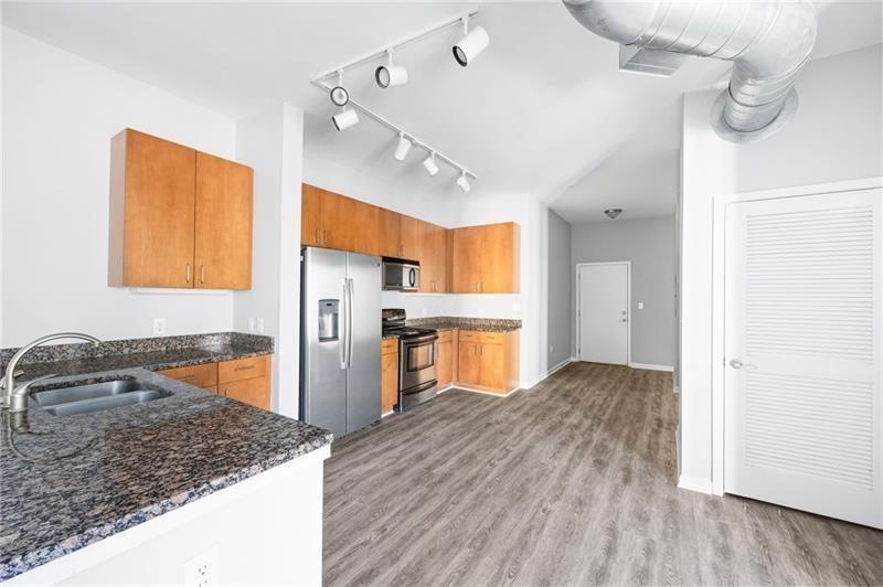 5300 Peachtree Road, Unit 2309 Chamblee, GA 30341 - Photo 5 of 44 a kitchen with stainless steel appliances granite countertop a refrigerator a sink dishwasher a stove and white countertops with wooden floor