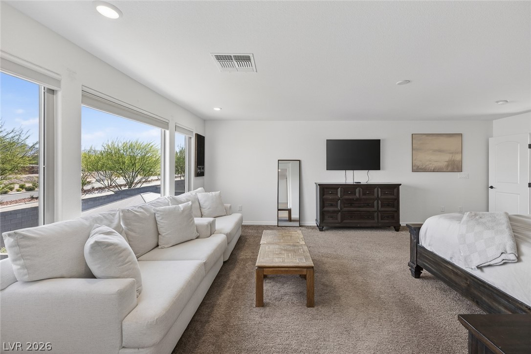 10446 Emerald Rye Street Las Vegas, NV 89183 - Photo 22 of 37 This primary bedroom offers generous proportions and sun-filled views through its expansive window line.