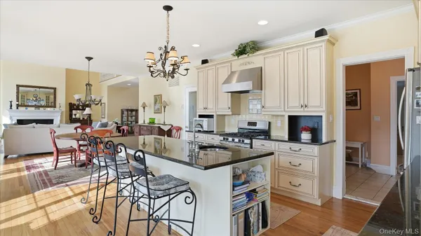 a kitchen with stainless steel appliances kitchen island granite countertop a stove a refrigerator a sink a dining table and chairs with wooden floor