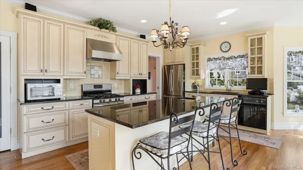 a kitchen with stainless steel appliances granite countertop a refrigerator a stove a sink a dining table and chairs with wooden floor