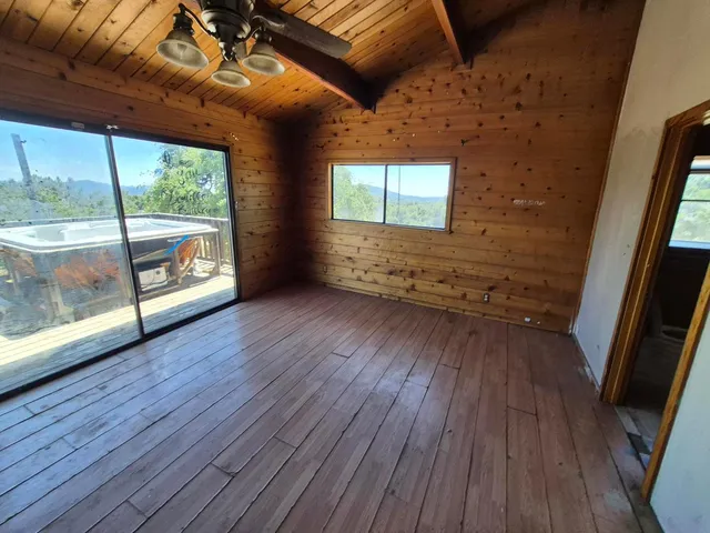 a view of an empty room with wooden floor and windows