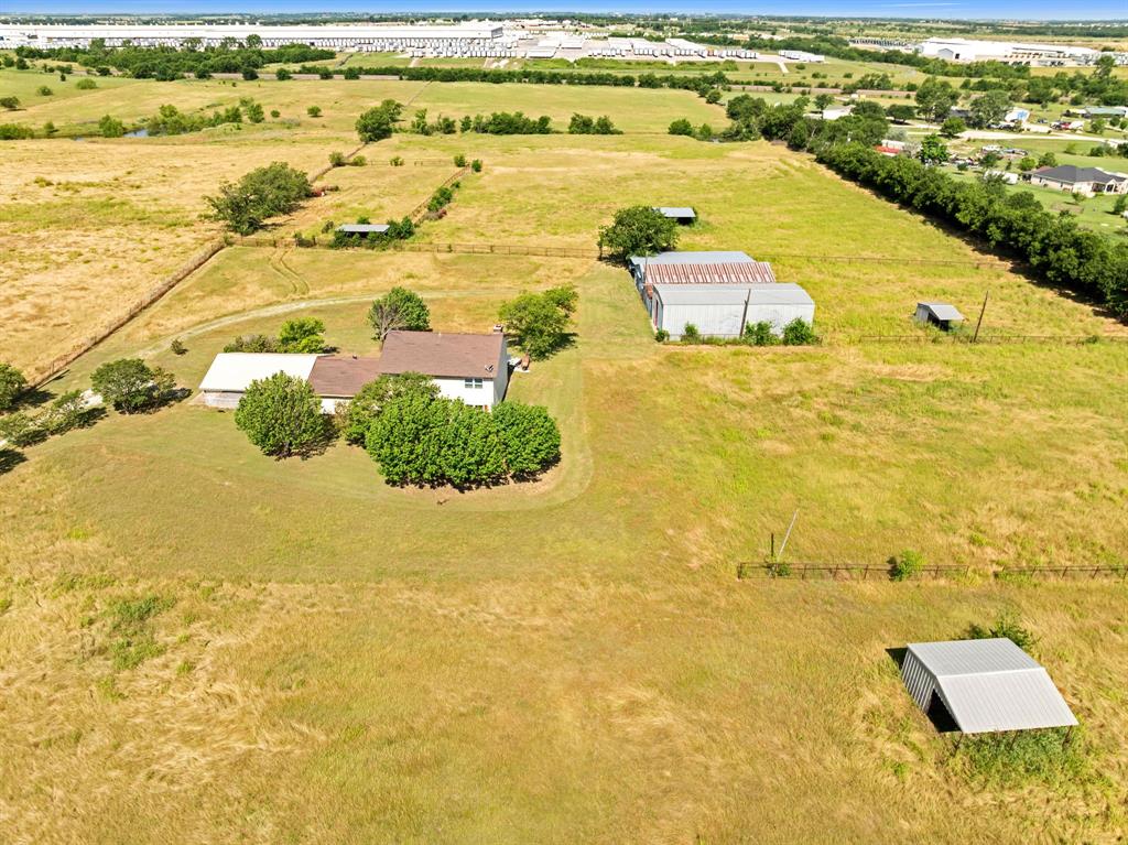 1795 Melton Road Sanger, TX 76266 - Photo 17 of 17 Expansive rural property featuring a two-story home with a brown shingle roof, two large outbuildings with metal roofs, and a smaller shed with a metal roof