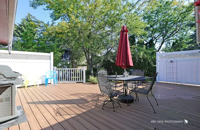 a view of a roof deck with table and chairs a barbeque with wooden floor and fence