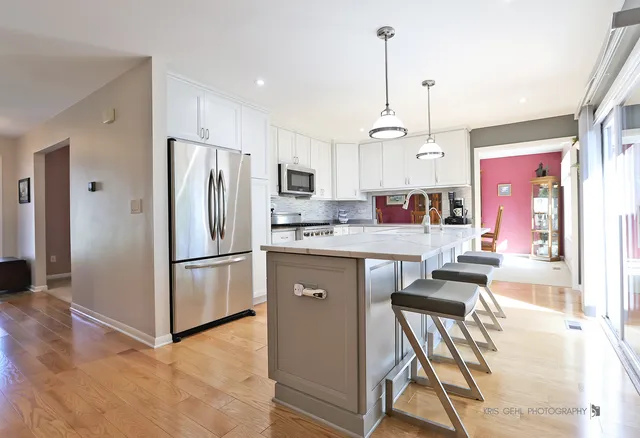 a kitchen with stainless steel appliances granite countertop a refrigerator a sink a stove and a wooden floors