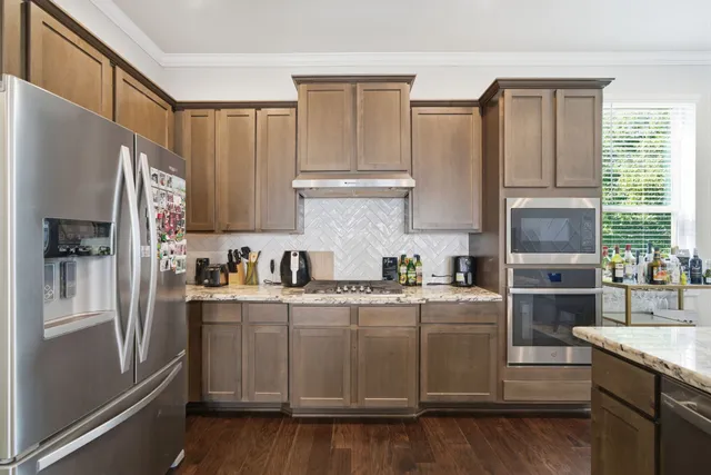 a kitchen with stainless steel appliances granite countertop a refrigerator a sink dishwasher a stove and white countertops with wooden floor