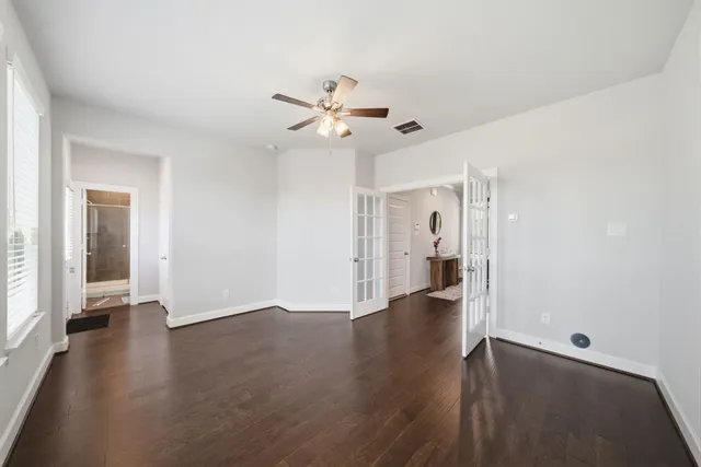 a view of a hallway with wooden floor and a ceiling fan