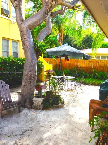 a view of a patio with table and chairs potted plants and a palm tree