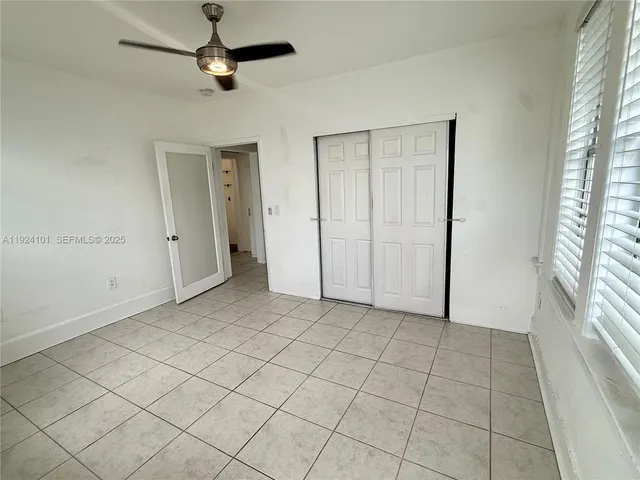 an empty room with windows and fan