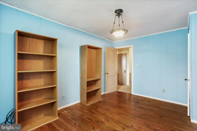 a view of a white house with a large tree and wooden fence