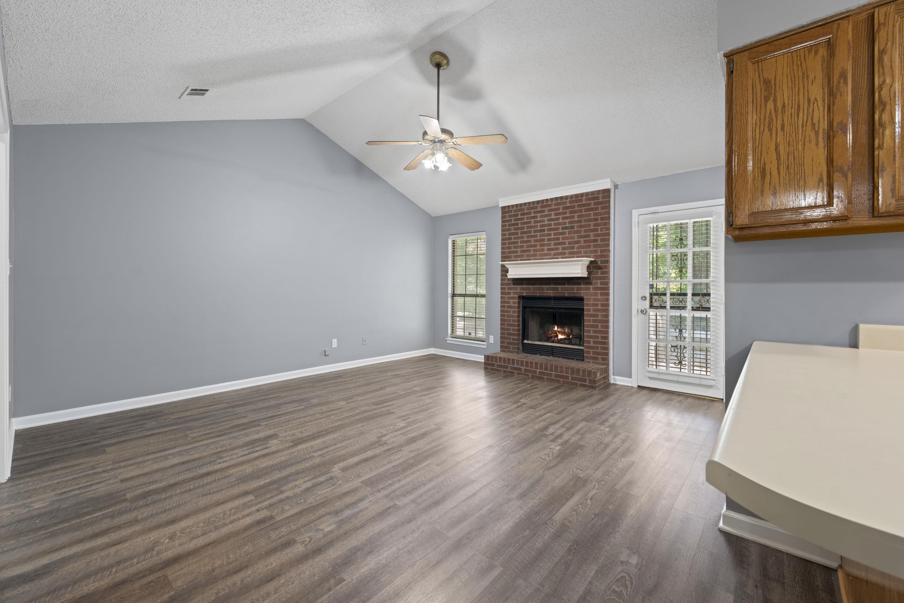 2252 Mangum Road Memphis, TN 38134 - Photo 6 of 23 Spacious interior with vaulted ceilings, wood-finish flooring, a brick fireplace with mantel, and a ceiling fan