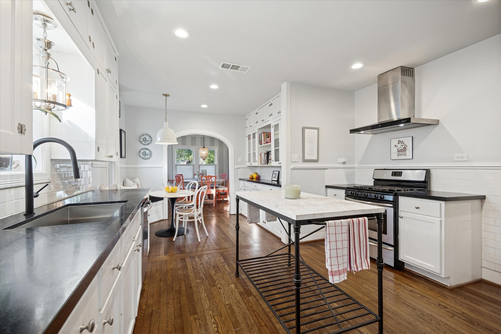 2109 Colquitt Street Houston, TX 77098 - Photo 12 of 28 An open view of the kitchen highlights hardwood floors, recessed lighting, and a seamless connection to the dining room beyond.