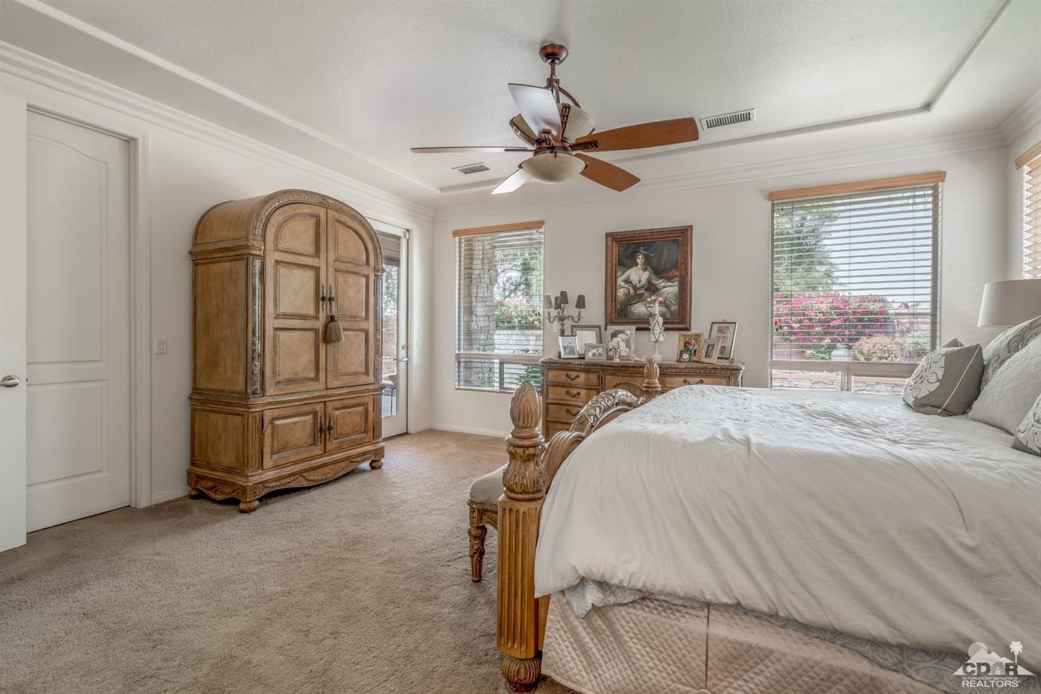 145 Via Solaro Rancho Mirage, CA 92270 - Photo 23 of 40 a spacious bedroom with a bed and a chandelier