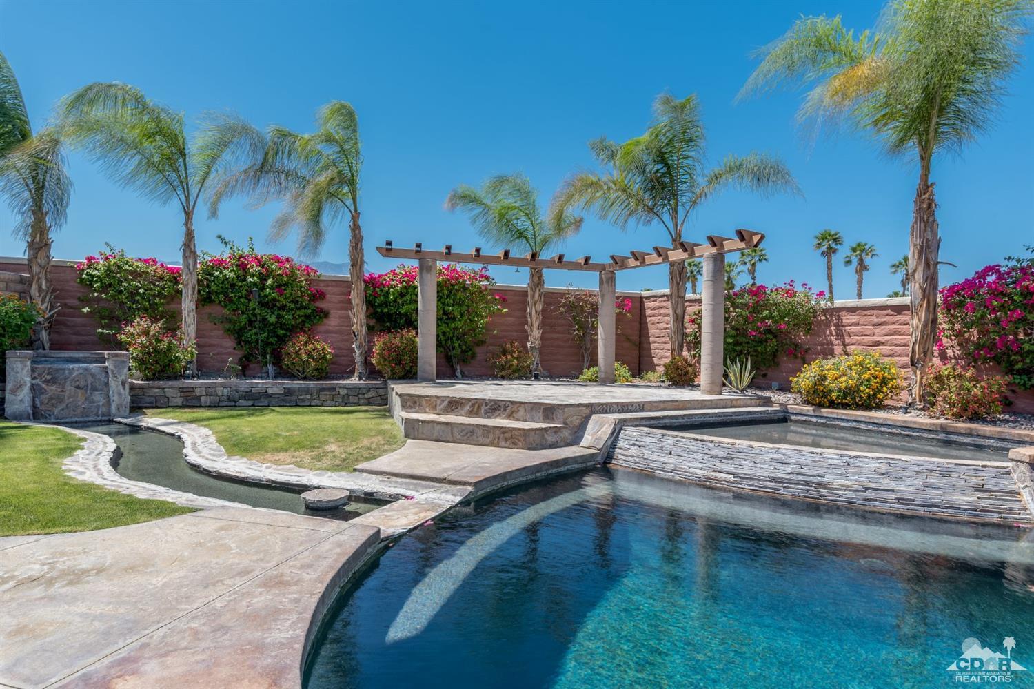 145 Via Solaro Rancho Mirage, CA 92270 - Photo 28 of 40 a view of a swimming pool with a lawn chairs under palm trees
