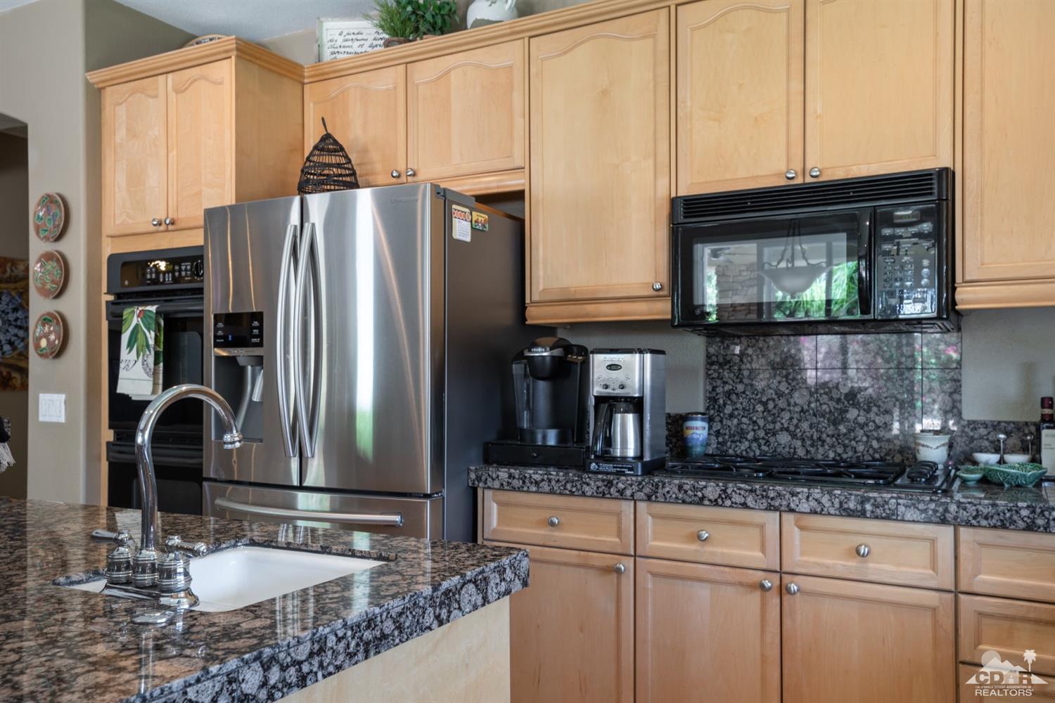 145 Via Solaro Rancho Mirage, CA 92270 - Photo 5 of 40 a kitchen with stainless steel appliances granite countertop a sink a refrigerator and cabinets