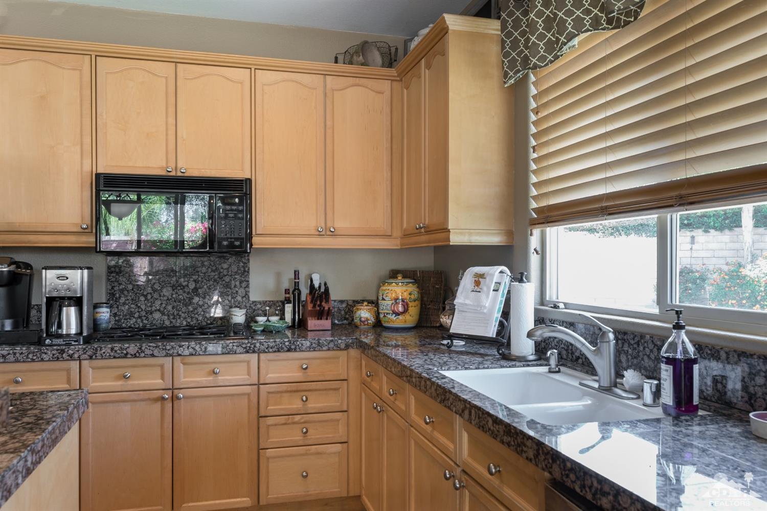 145 Via Solaro Rancho Mirage, CA 92270 - Photo 6 of 40 a kitchen with stainless steel appliances granite countertop a sink a stove and white cabinets