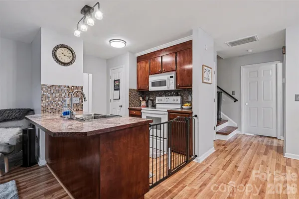 a kitchen with stainless steel appliances granite countertop a refrigerator a stove top oven a chimney and wooden floor