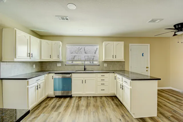 a kitchen with granite countertop white cabinets and white appliances