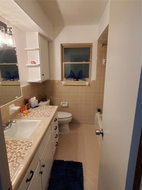 7424 Walling Lane Dallas, TX 75231 - Photo 16 of 19 a bathroom with a sink a toilet and mirror