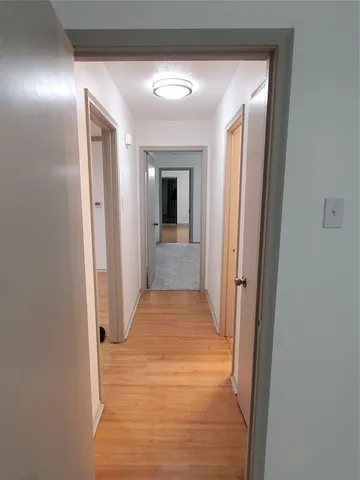 a view of a hallway with wooden floor and a bathroom