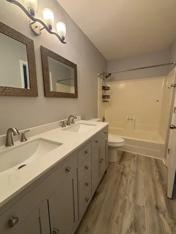 a bathroom with a double vanity sink toilet mirror and bathtub