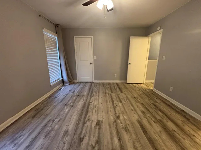 an empty room with wooden floor closet and windows