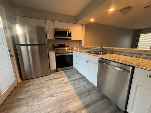 a kitchen with stainless steel appliances granite countertop a refrigerator a stove a sink and a microwave