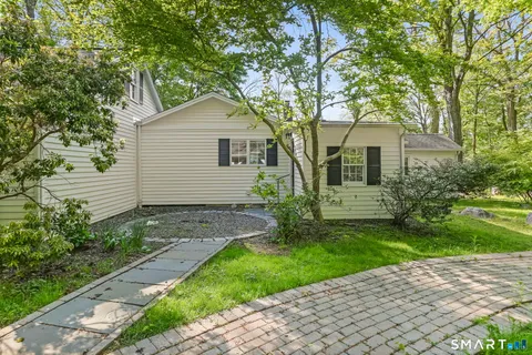 a view of a white house next to a yard with big trees