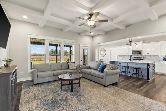 a living room with furniture kitchen view and a large window