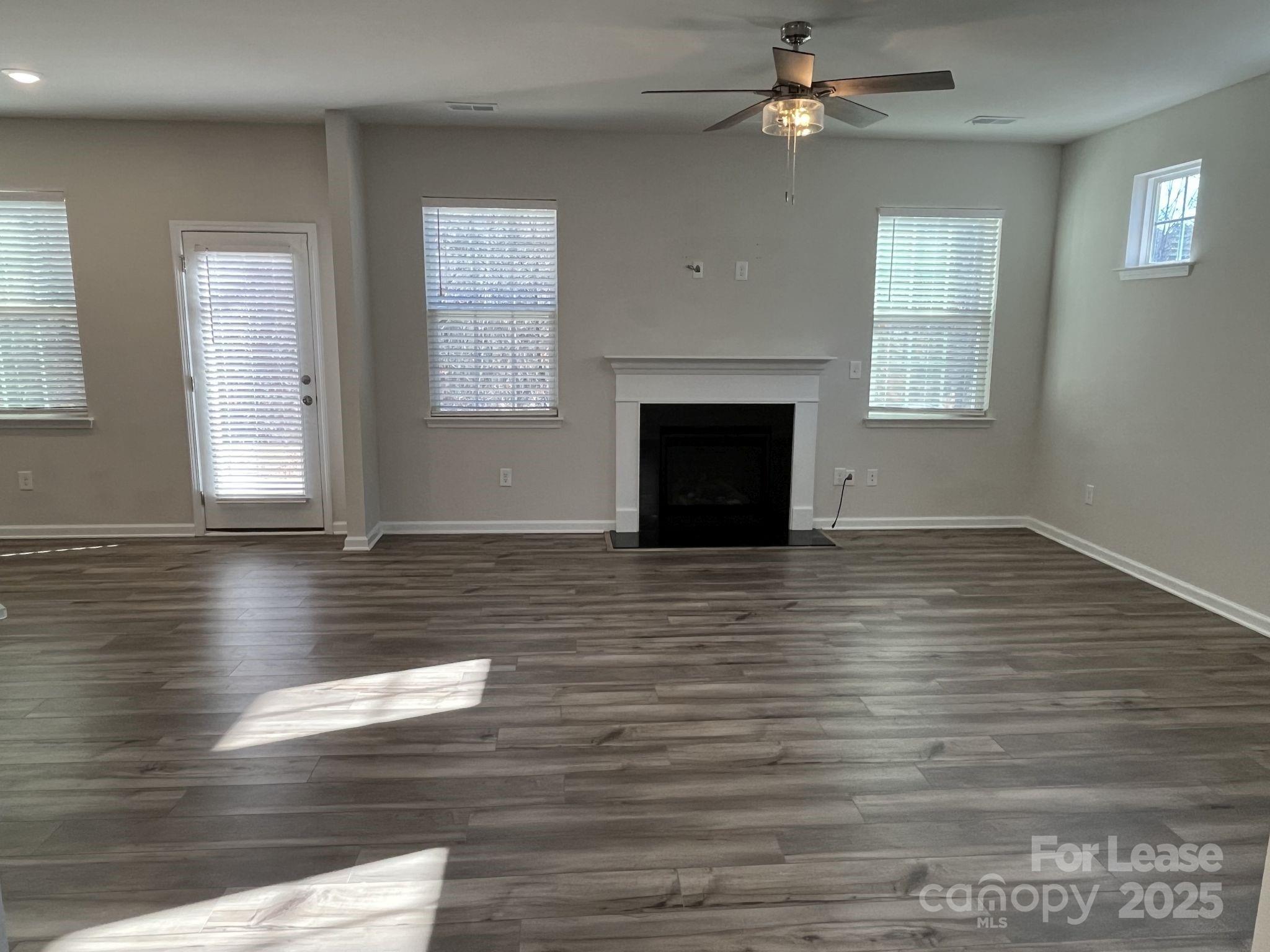 15529 Capps Road Charlotte, NC 28278 - Photo 5 of 27 an empty room with wooden floor fireplace and windows