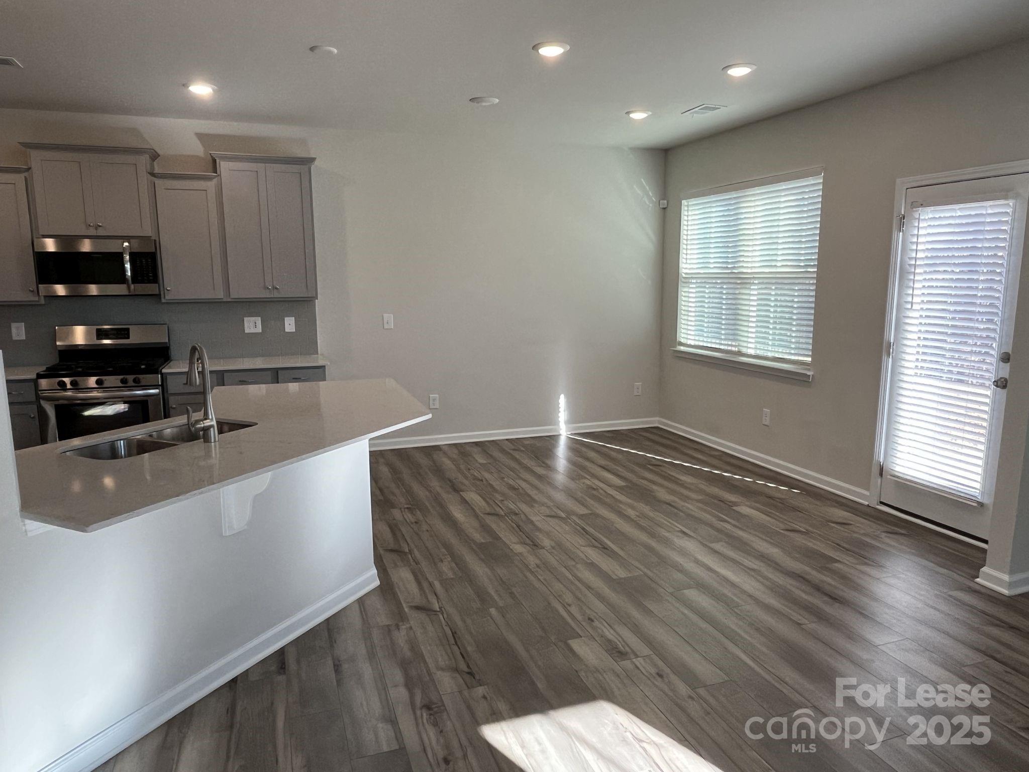 15529 Capps Road Charlotte, NC 28278 - Photo 7 of 27 a large kitchen with stainless steel appliances a large counter top a stove and a wooden floors