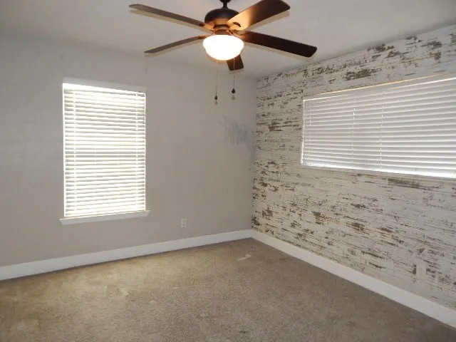 an empty room with a window and a ceiling fan