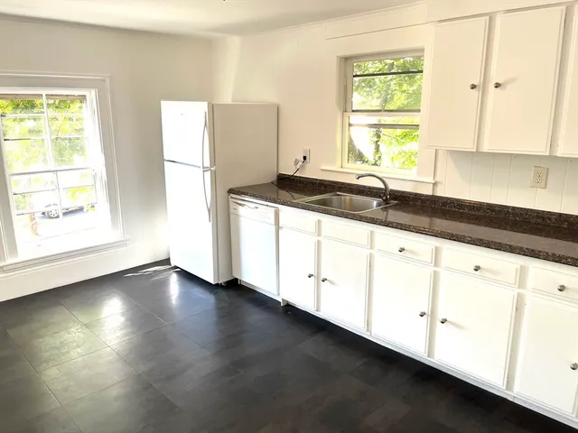 a kitchen with granite countertop white cabinets and a window