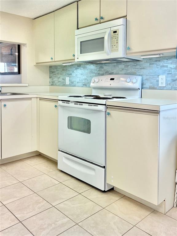 6501 Stone River Road, Unit 203 Bradenton, FL 34203 - Photo 12 of 45 a kitchen with granite countertop white cabinets and white appliances