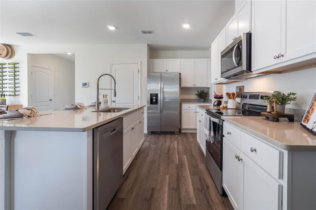 3413 Nettle Loop Tavares, FL 32778 - Photo 12 of 29 a kitchen with stainless steel appliances granite countertop a sink a stove and a refrigerator