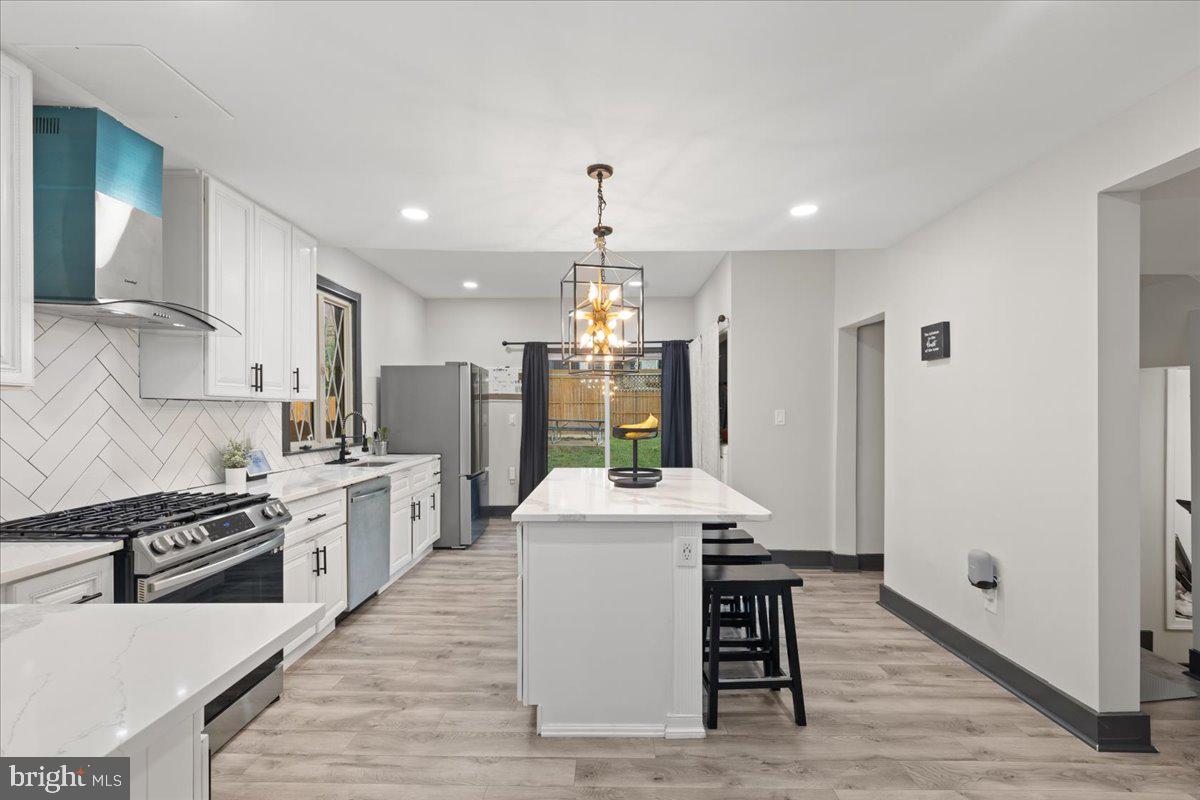 3910 Chatham Road Baltimore, MD 21207 - Photo 15 of 71 a kitchen with stainless steel appliances granite countertop a stove top oven a sink dishwasher and a refrigerator with wooden floor